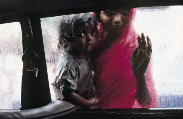 INDIEN. Bombay. 1993. En mor og et barn tigger gennem vinduet i en taxa under monsunen